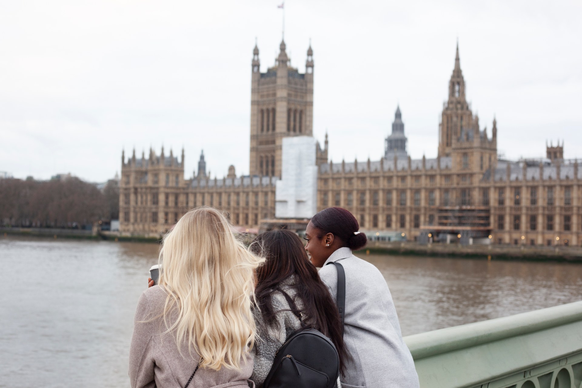Londra’da Thames kıyısında üç genç kadın, arka planda Westminster Sarayı